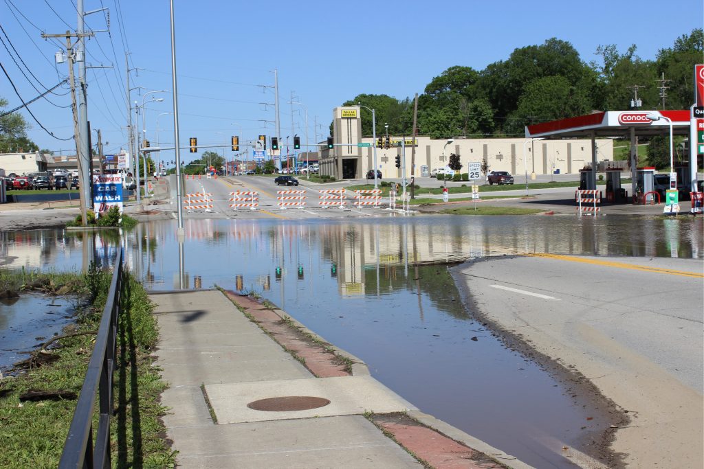 Photo of a flooded street with businesses in the background.