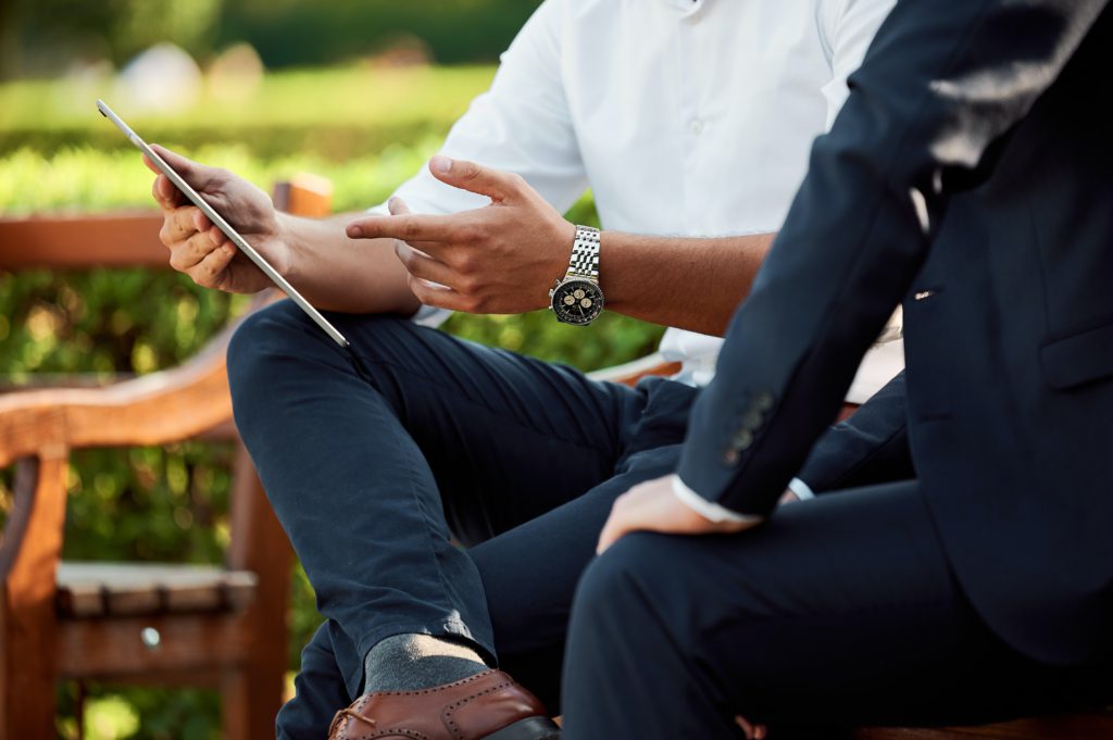 Two men discussing information on a tablet.